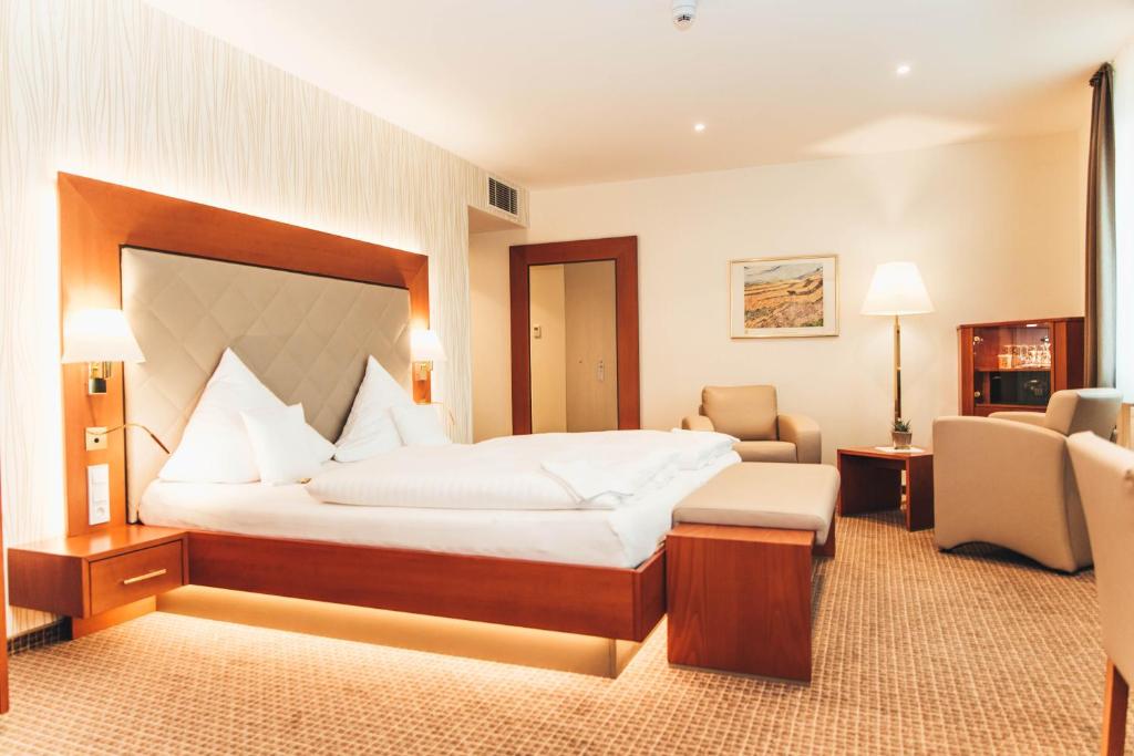 ein Hotelzimmer mit einem großen Bett und Stühlen in der Unterkunft Ringhotel Teutoburger Wald in Tecklenburg