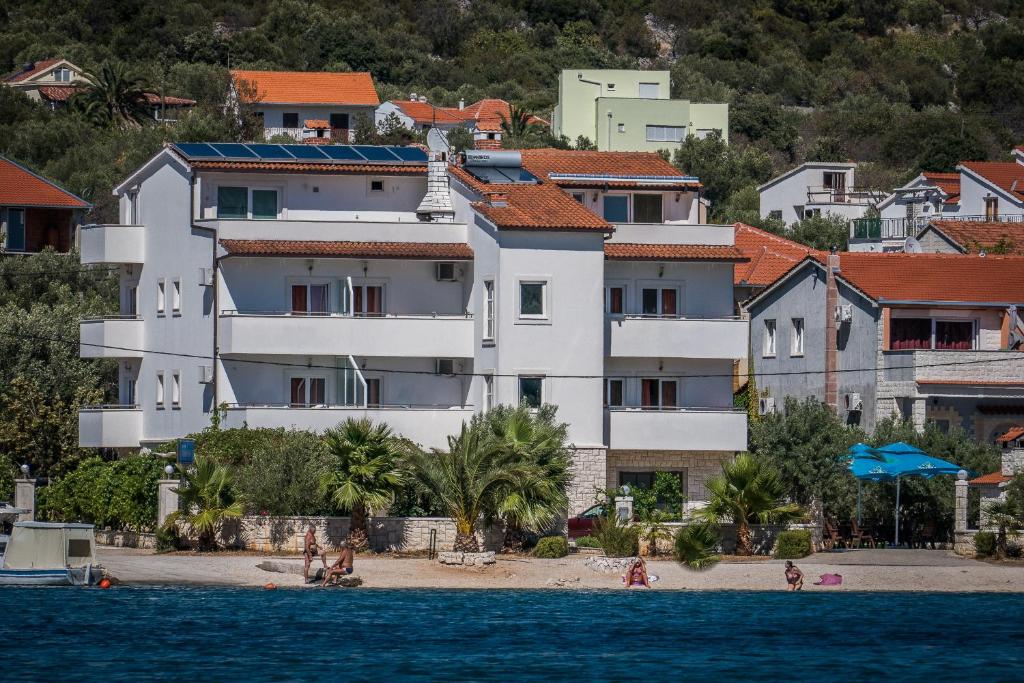 a large white building on a beach with houses at Villa Albatros in Vinišće