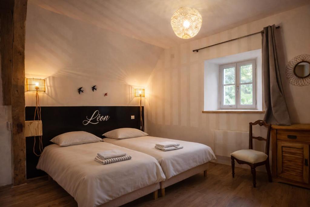 a bedroom with two beds with white sheets and a window at Gîte Léon - Au cœur du village 4 pers in Gargilesse-Dampierre