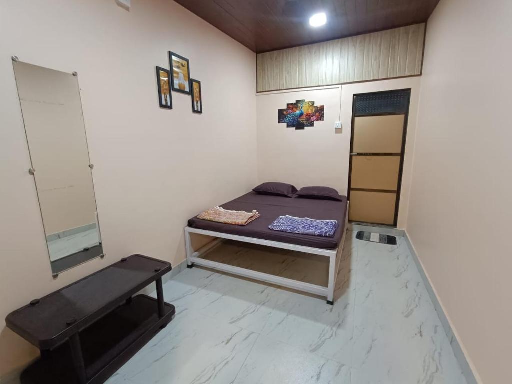a room with a bed and a bench in it at Aagman Homestay in Srīvardhan