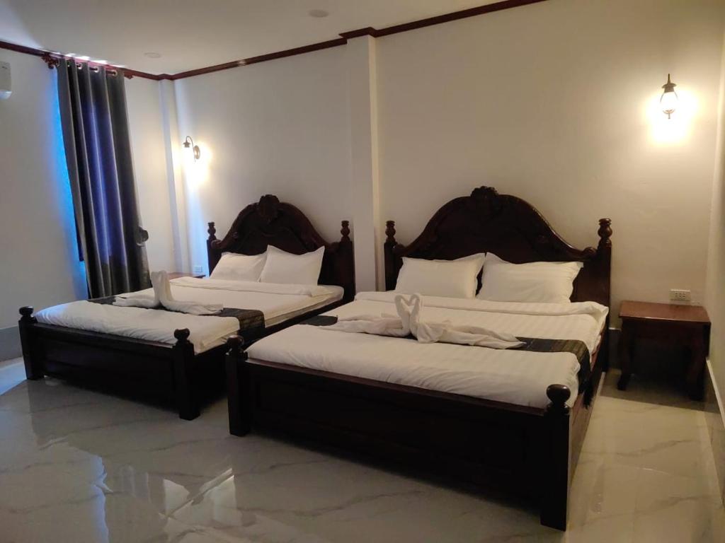 two twin beds in a room with two lamps at Villa ThreeD Xaydara in Luang Prabang