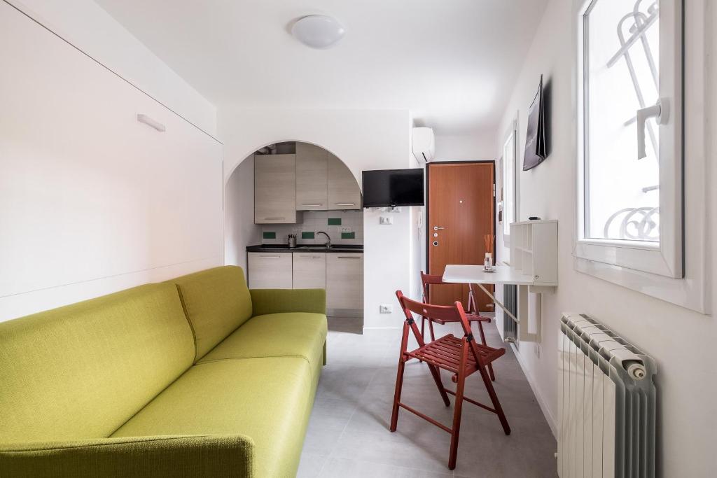 a living room with a green couch and a kitchen at Piccola dimora Casalecchio vicino al GranReno e Unipol in Zola Predosa