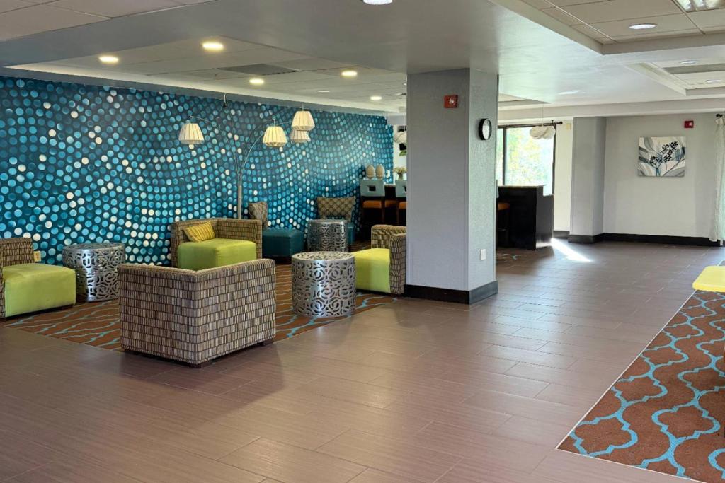 a lobby with a waiting area with green chairs and blue tiles at Comfort Inn & Suites Tampa North I-75 in Tampa
