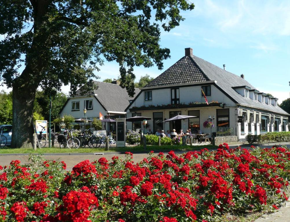 a white building with red flowers in front of it at Hotel de Koningsherberg in Anloo