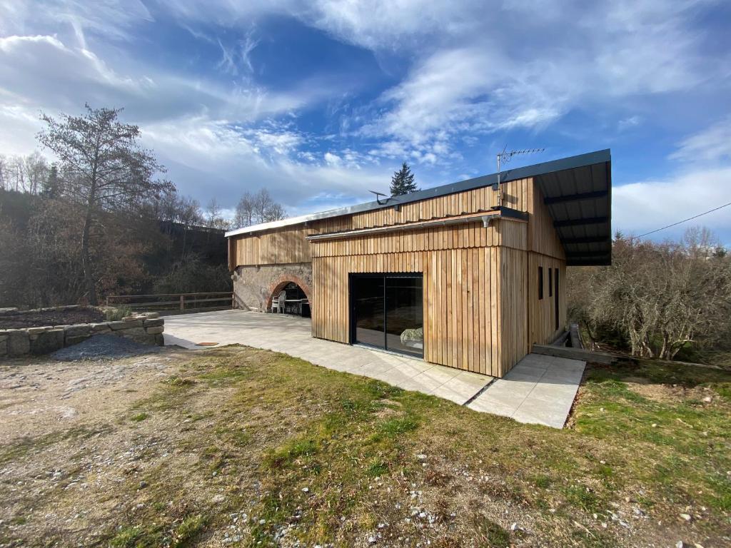 a large wooden building with a garage in a field at La Vieille Scierie in Basville