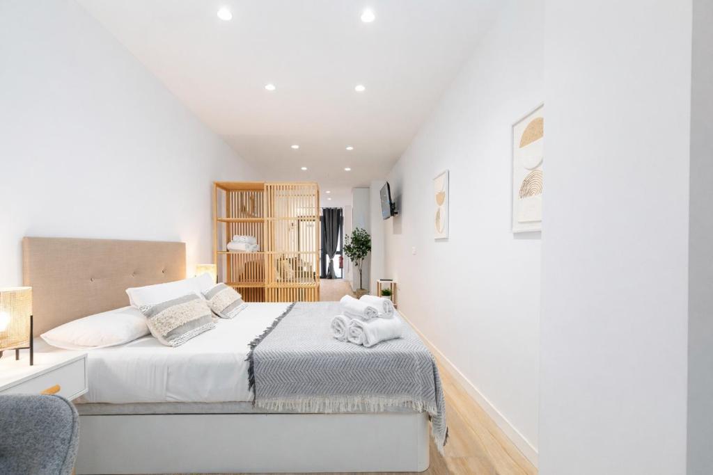 a white bedroom with a bed and a chair at Valencia Marina Apartment near Beach & City of Arts in Valencia