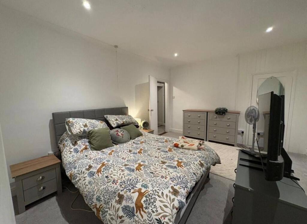 a bedroom with a bed and a flat screen tv at Spacious 3-Bed Terrace, Great Links in Stowmarket