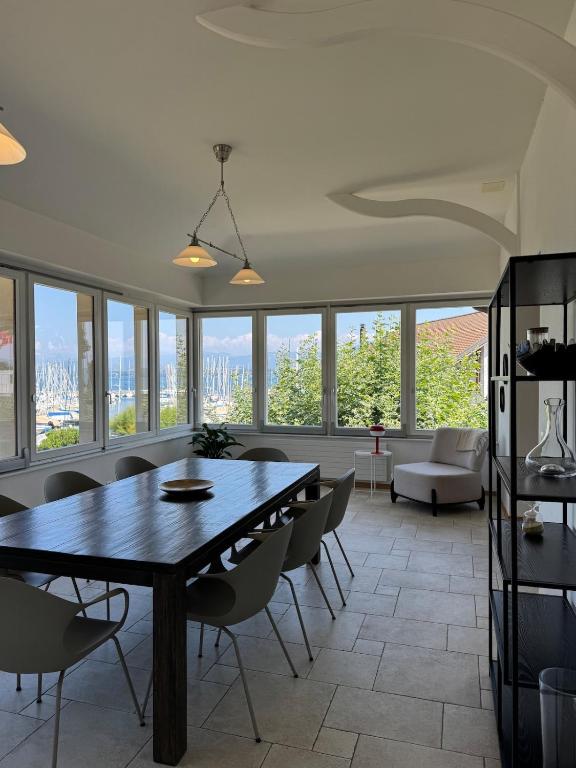 a dining room with a table and chairs and windows at Exceptional house by Lake Geneva in Versoix