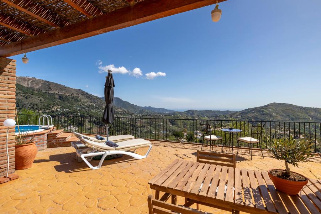 a patio with chairs and a table and an umbrella at Casa Mira in Cómpeta