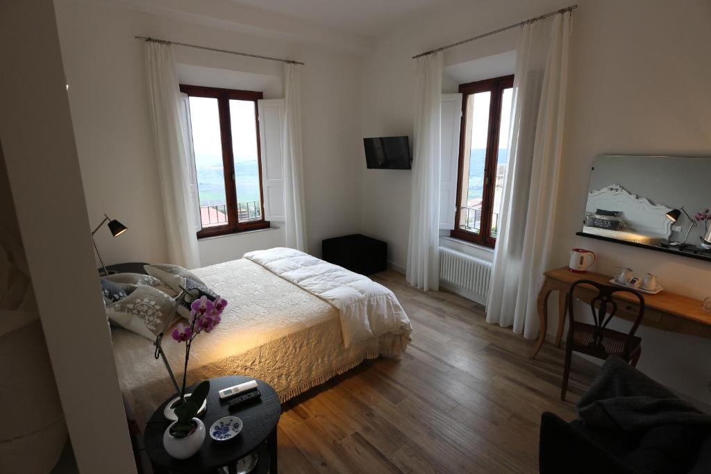 a bedroom with a bed and a desk and two windows at AL 32 B&B in Massa Marittima