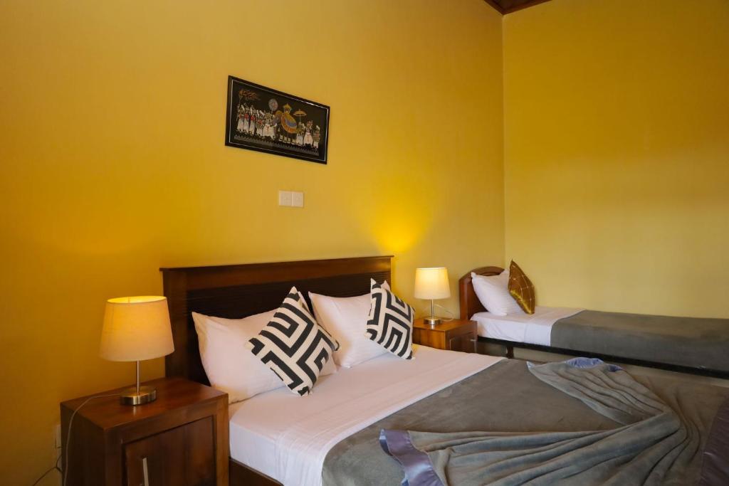 two beds in a room with yellow walls at Grosvenor Hotel in Nuwara Eliya