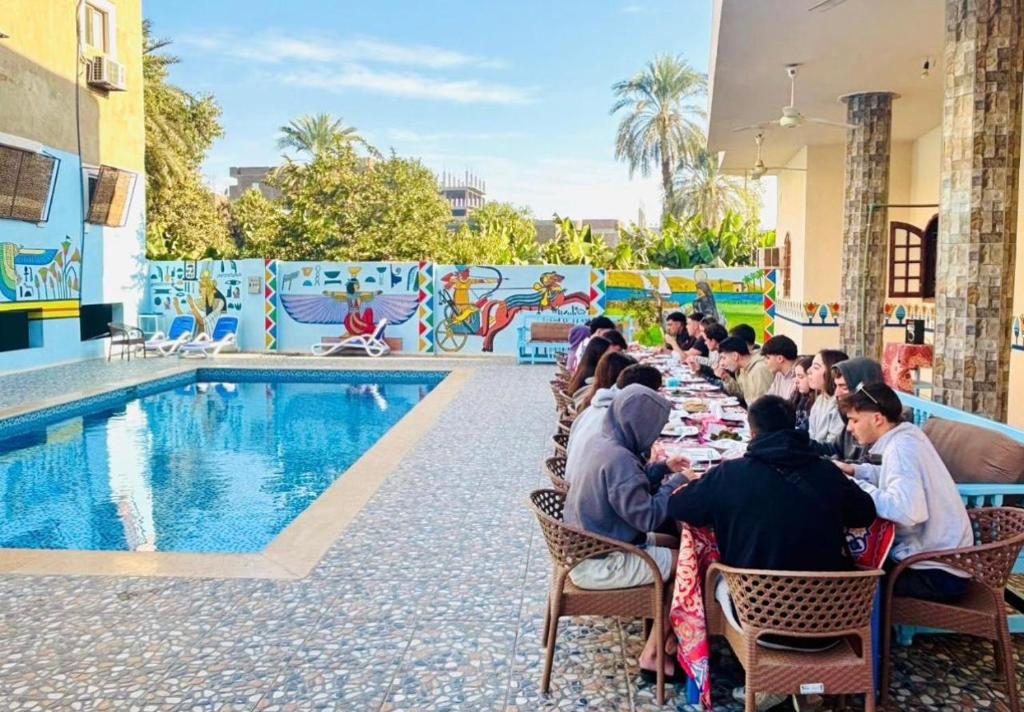 a group of people sitting at a table by a pool at mountain Luxor in Al Aqālitah