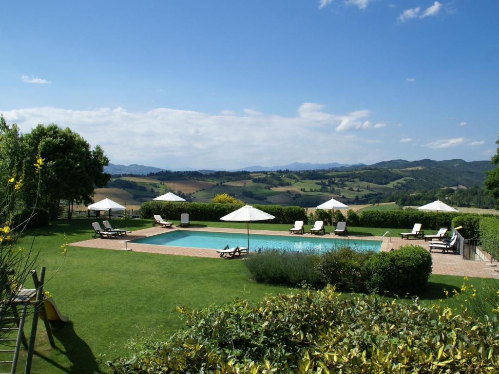 una piscina con sillas y sombrillas en un jardín en Spacious Holiday Home in Montone, en Montone