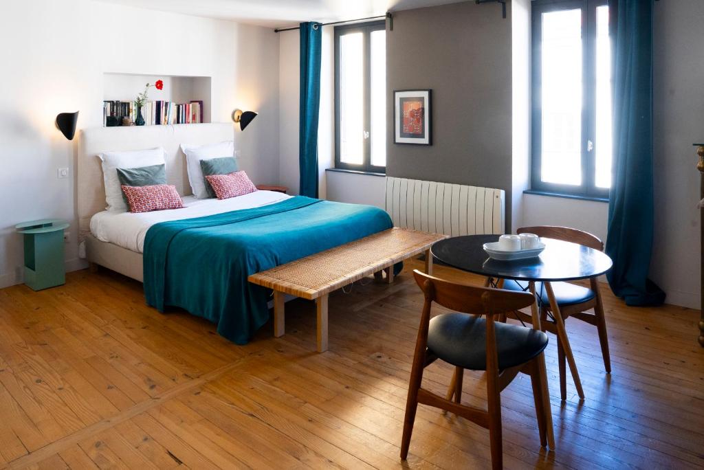 a bedroom with a bed and a table and chairs at La Tour Grégoire in Clermont-Ferrand