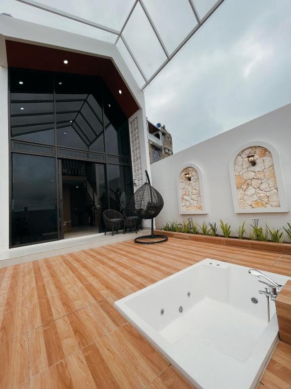 a large room with a white tub in the middle of a wooden floor at Villa with jacuzzi, Damar Ningrum 5 in Panjadakan