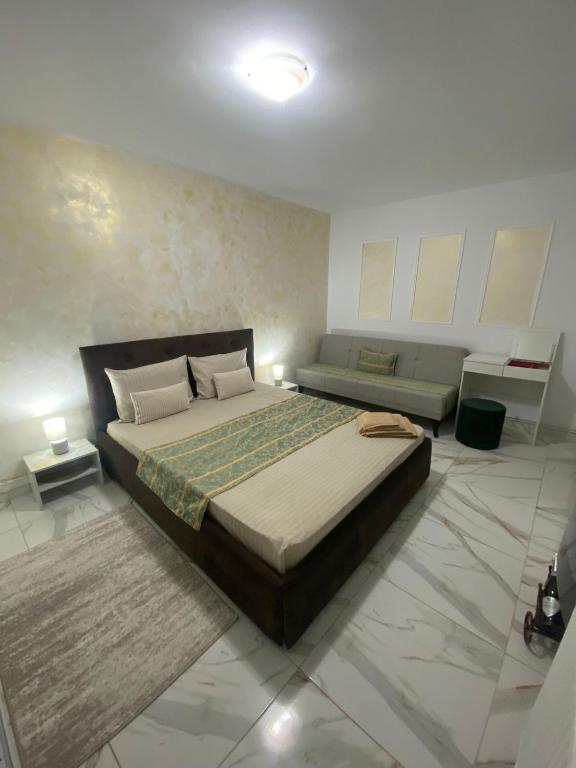 a bedroom with a large bed and a couch at Lemora Apartments 1 in Focşani