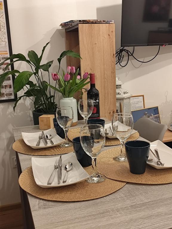 a table with plates and wine glasses on it at Przystanek Piechowice in Piechowice