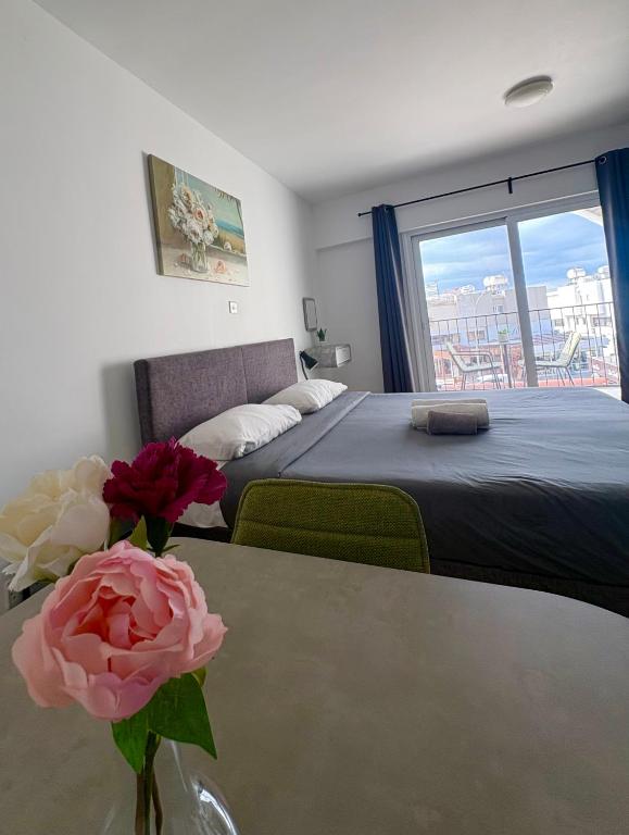 a bedroom with a bed and a vase of flowers on a table at Rimini Balcony Studios - Steps from the Sea in Paphos