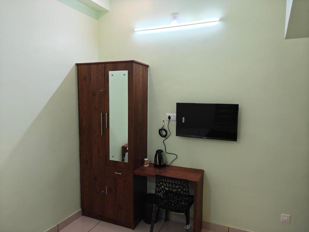 a room with a cabinet and a tv on a wall at Sivasakthi Inn in Trivandrum