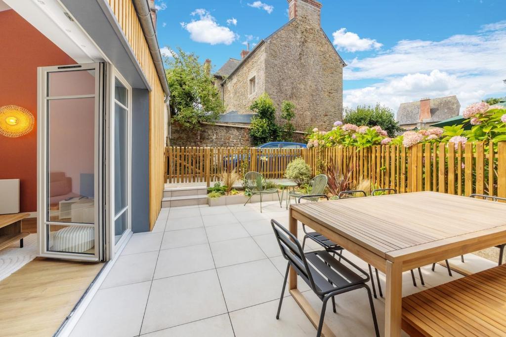 a patio with a wooden table and chairs at Belle maison 8 personnes à 600m de la plage avec parking privé in Dinard