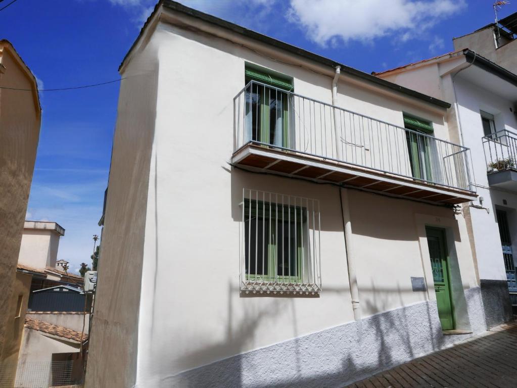 a white building with green windows and a balcony at La casita verde in Cazorla