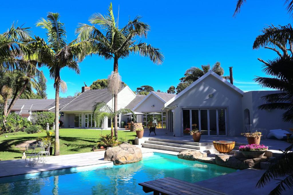 a house with a swimming pool and palm trees at Vitry Country Estate in Gqeberha