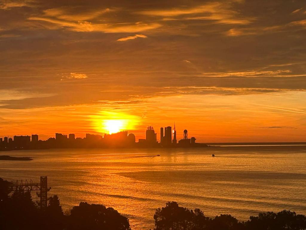 a sunset over a body of water with a city at Touch the Coast in Batumi
