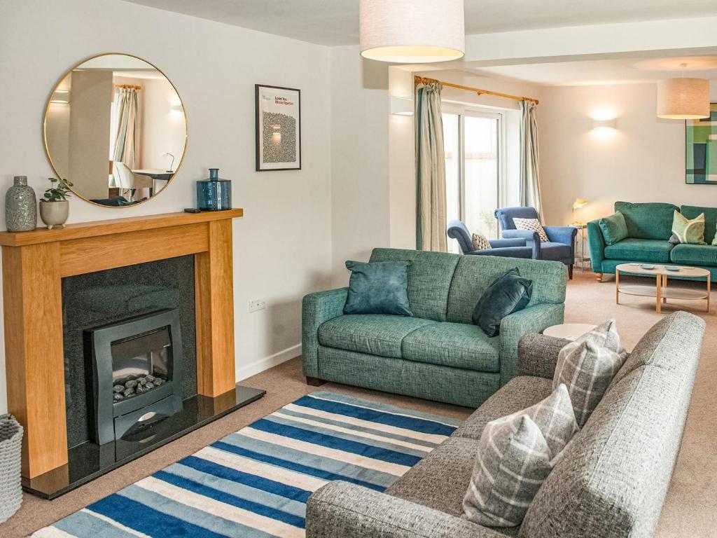 a living room with a fireplace and a green couch at Brooklands in Uplyme
