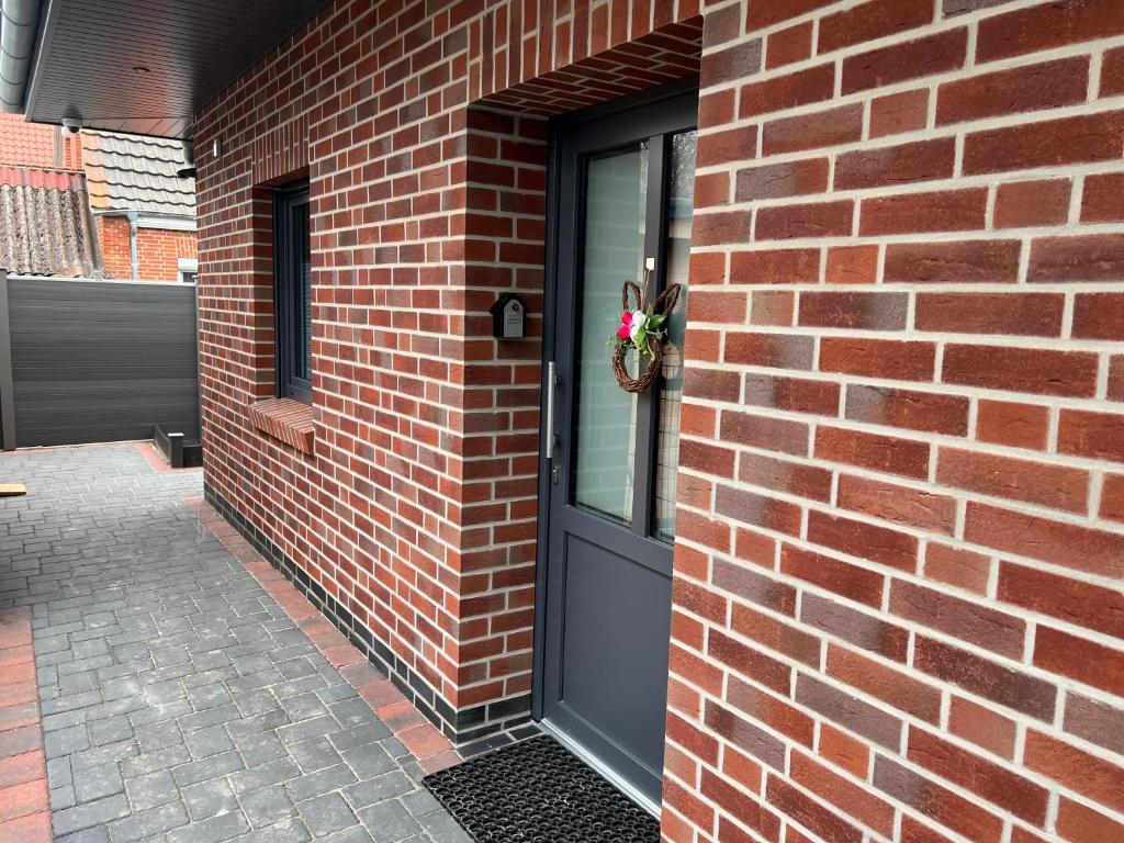 a brick building with a black door with a window at Barrierefreie Ferienwohnung Abendrot in Pewsum, 1 - 4 Personen in Krummhörn