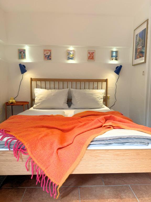 a bedroom with a bed with an orange blanket on it at Gästehaus Stefan Koch in Rust
