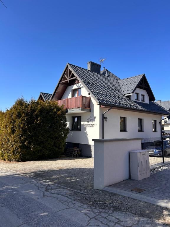 a white house with a gate and a fence at Apartamenty na Rycerskiej in Czorsztyn
