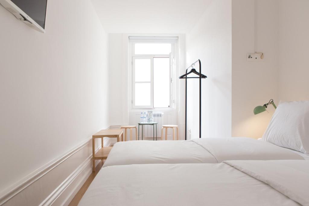 a white bedroom with two beds and a table at Porto Republica Riverside in Porto
