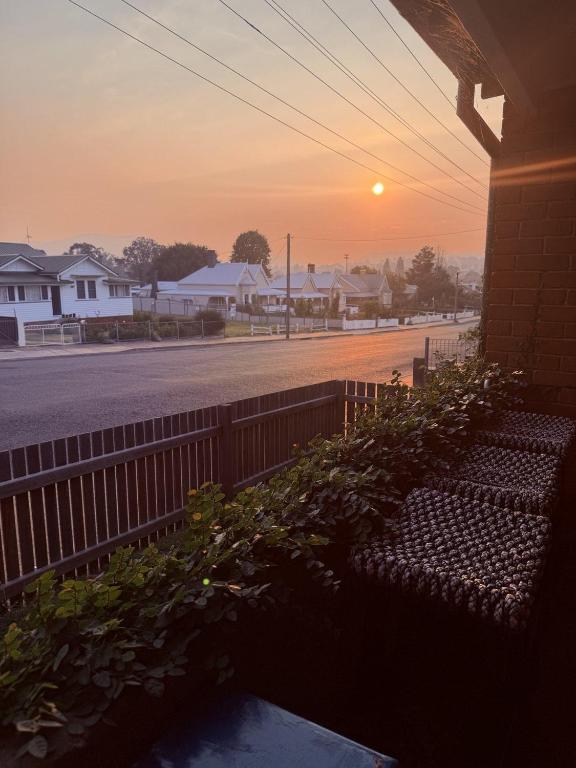 a sunset over a street with a bench and a fence at The Residence - Spacious 4-Bed Tenterfield Home in Tenterfield