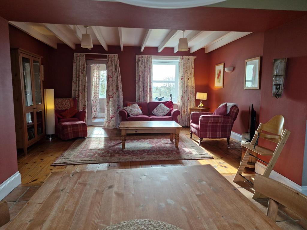 a living room with red walls and red furniture at Barcloy Milk House in Kirkcudbright