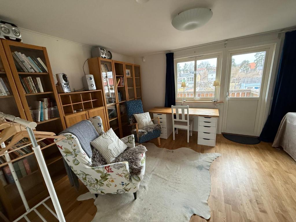 a living room with a desk and chairs and a table at Lägenhet 2 sovrum med vardagsrum och kök i villa med gemensam ingång in Stockholm