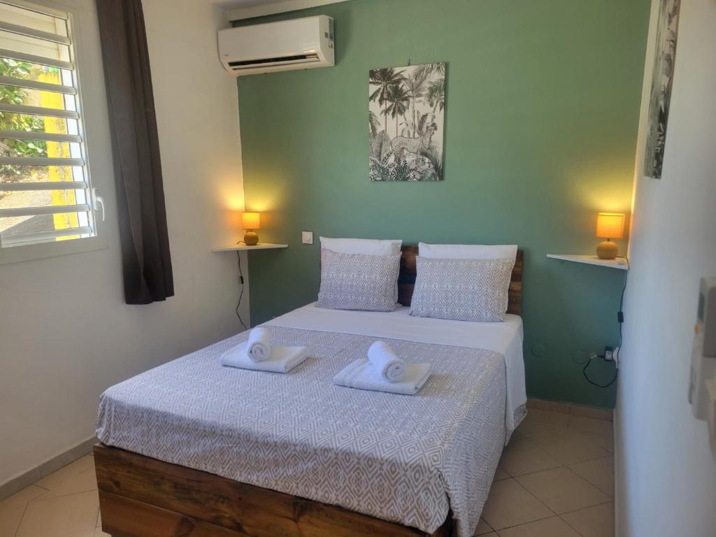 a bedroom with a bed with two towels on it at LE MANGO COSY ZEN proche de l'aéroport in Les Abymes