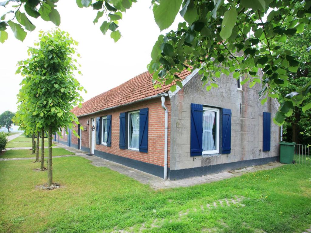 a brick house with blue windows and a tree at Holiday home in North Limburg with enclosed garden in Ospel