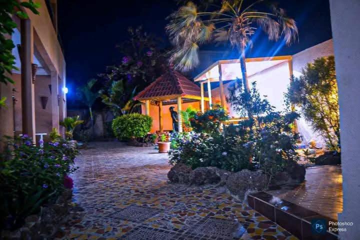 a courtyard with flowers and a gazebo at night at Résidence KEUR FLEURIE in Rufisque