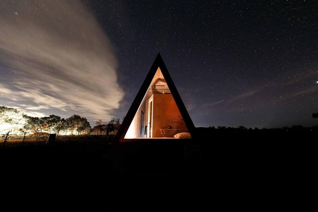 a small house with a triangular window at night at Romantic luxury tiny home in an idyllic setting in Glenquarry