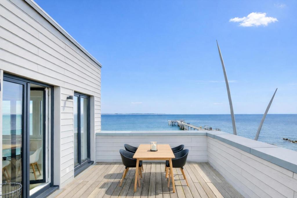 a patio with a table and chairs and the ocean at Ostsee Suite 2 - Penthouse in Niendorf