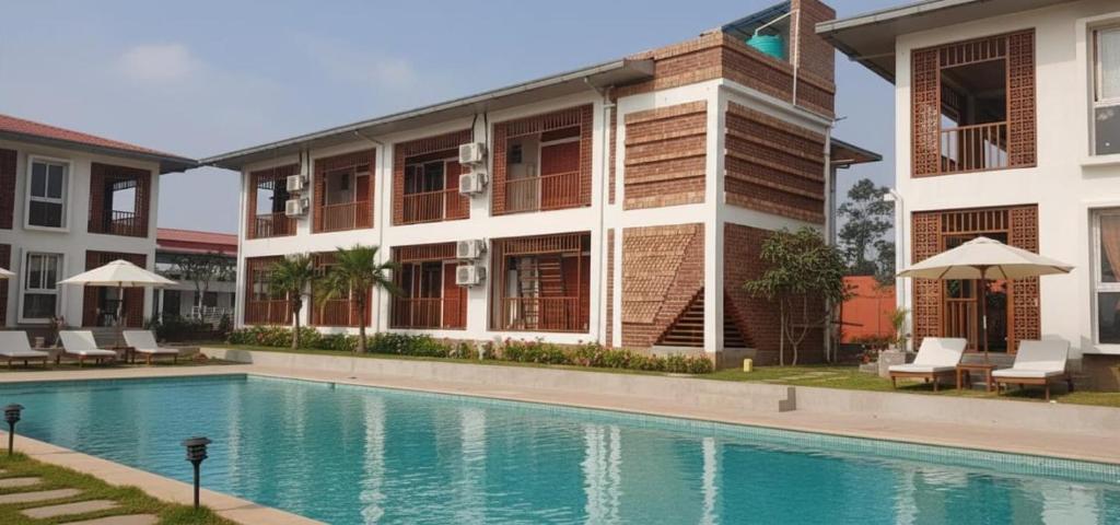 a hotel with a swimming pool in front of a building at Ankush Resort in Vishnupur