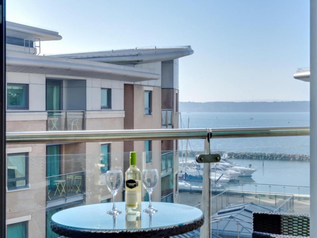 a table with two glasses of wine on a balcony at Reflections - Balcony Views of Poole Harbour in Poole