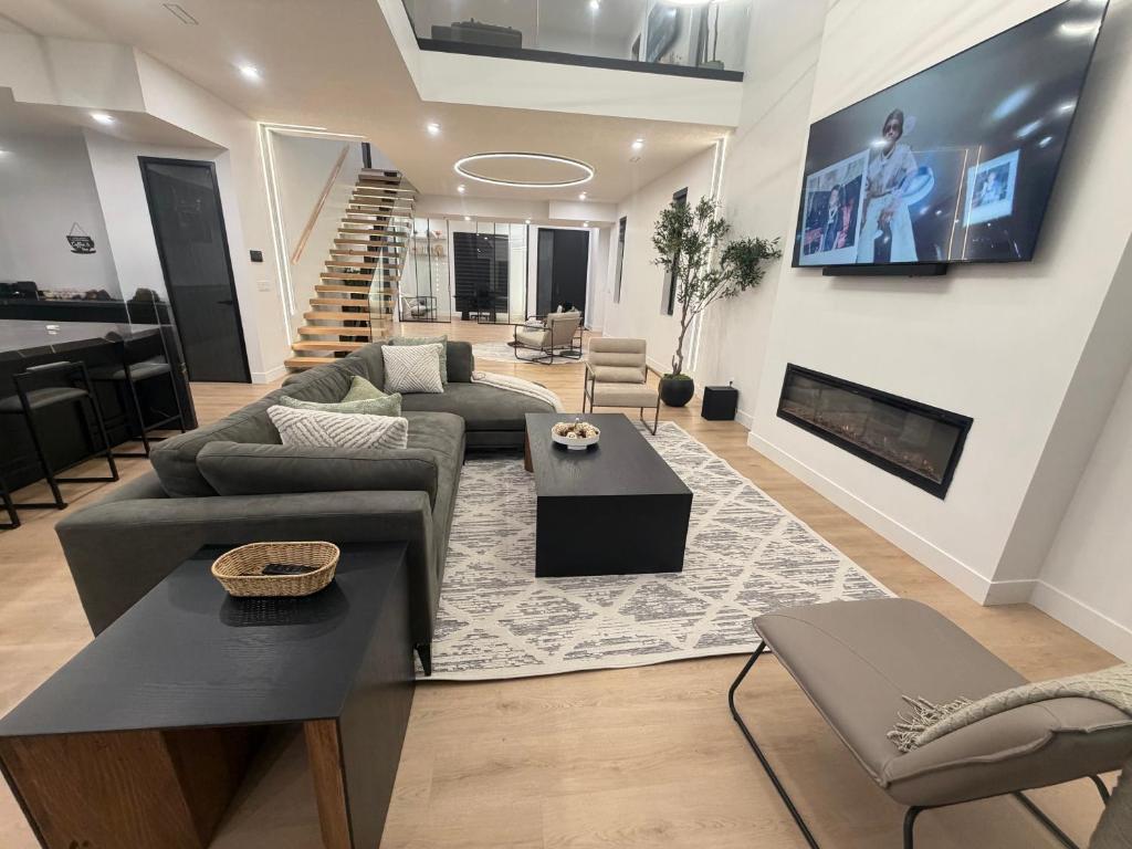 a living room with a couch and a tv on a wall at Downtown Luxe Stay - High River in High River