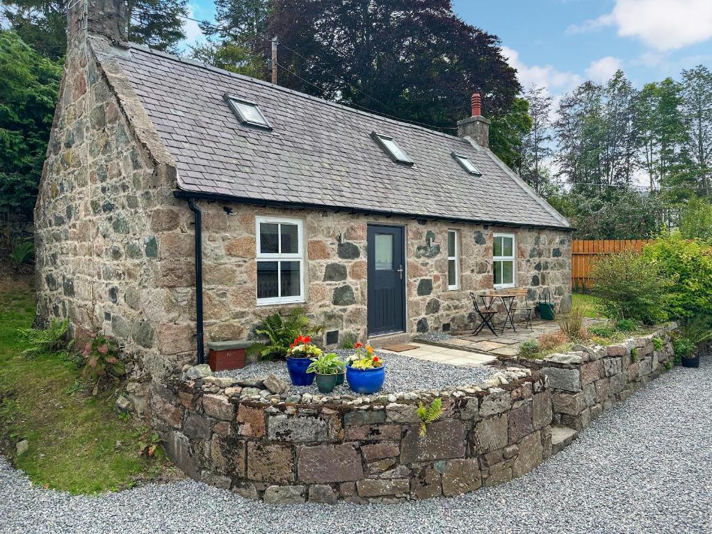 a small stone house with a stone wall at Wagglehead Cottage in Aboyne