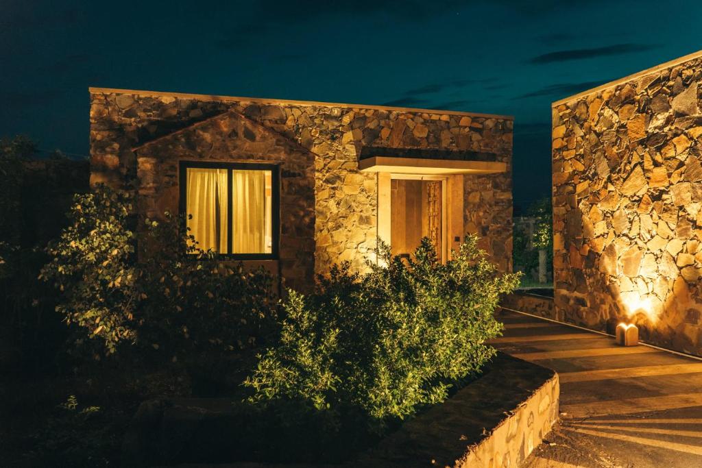 a stone house with a lit up door at night at Meladin Sariska in Tehla