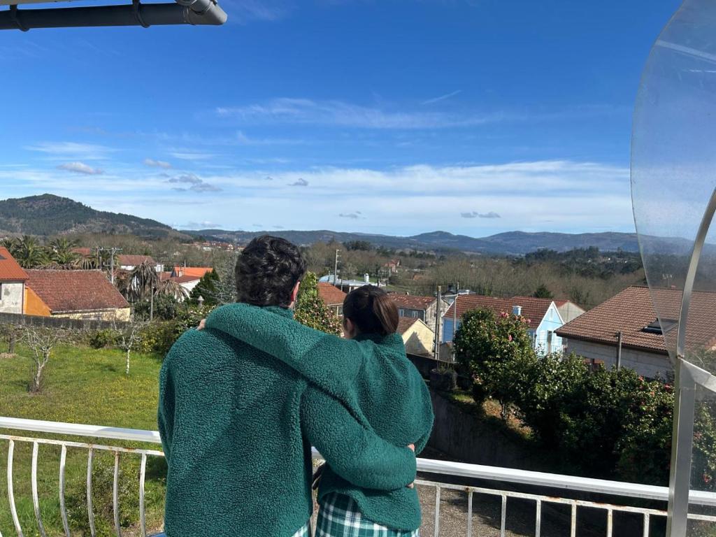 a man and woman standing on a balcony looking out at the mountains at La maison d'Abelleira in Puenteareas