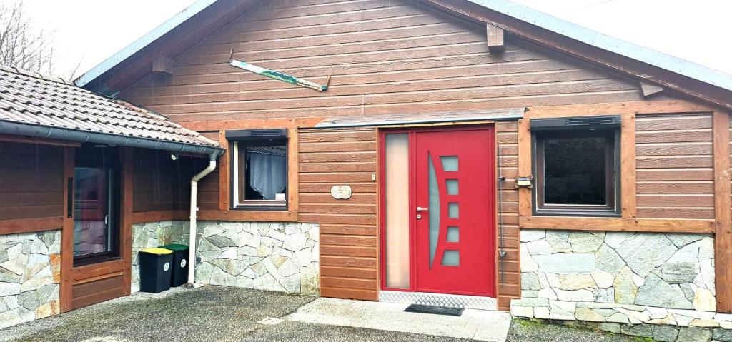 a red door on a house with a stone wall at Le Chalet des Côtes in Cornimont