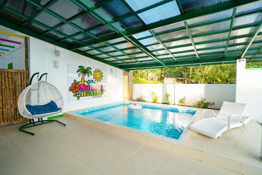a swimming pool in a house with a ceiling at SunDay Hostel in Siquijor