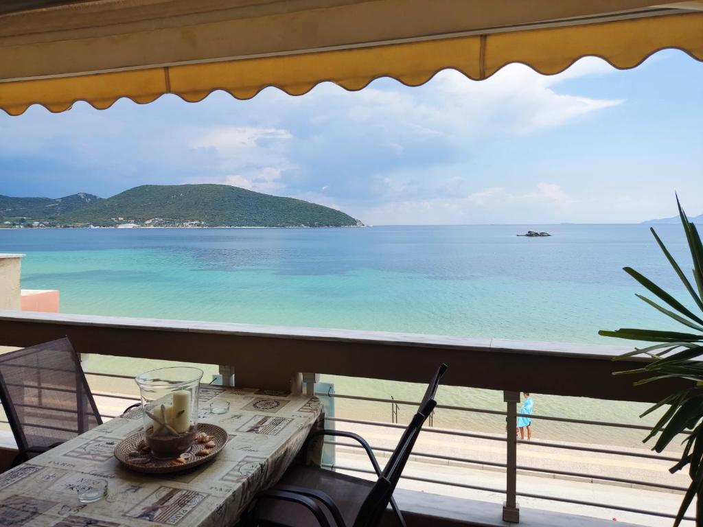 a table with a drink on a balcony overlooking the ocean at SeastheDayApartment in Nea Peramos