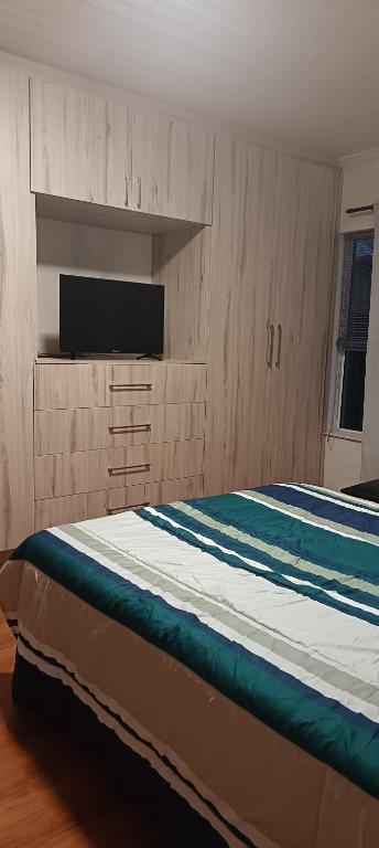 a bedroom with a bed with a flat screen tv at Large ensuite room in Goodwood